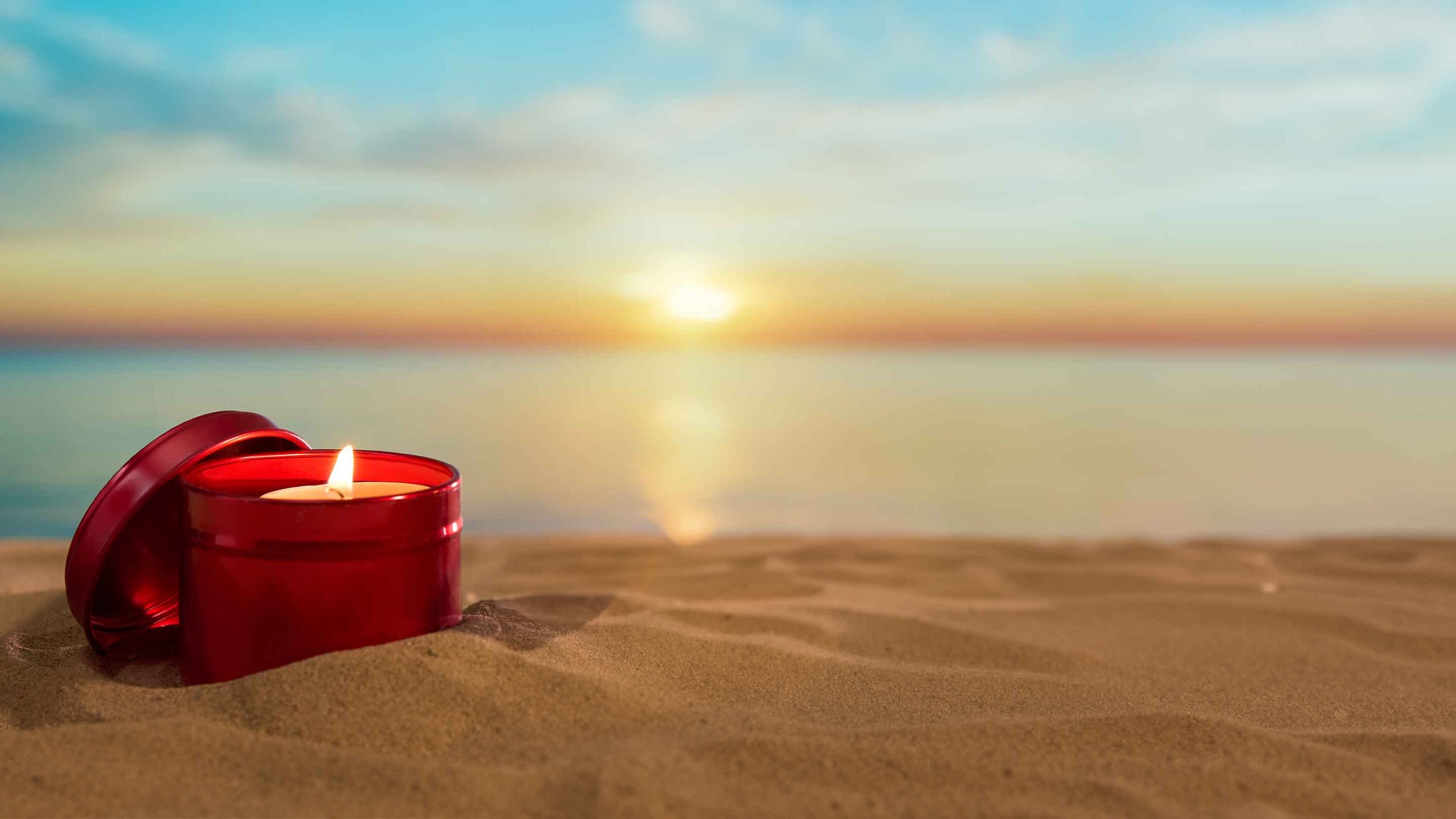 Confezione in latta di candela rossa sulla spiaggia