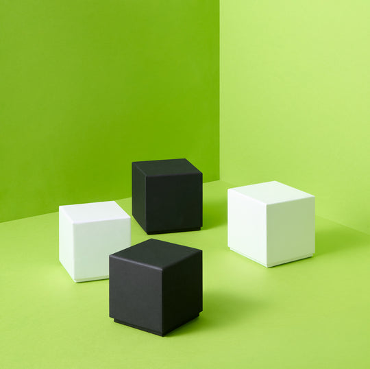 Scatole regalo rigide bianche e nere su sfondo verde 
